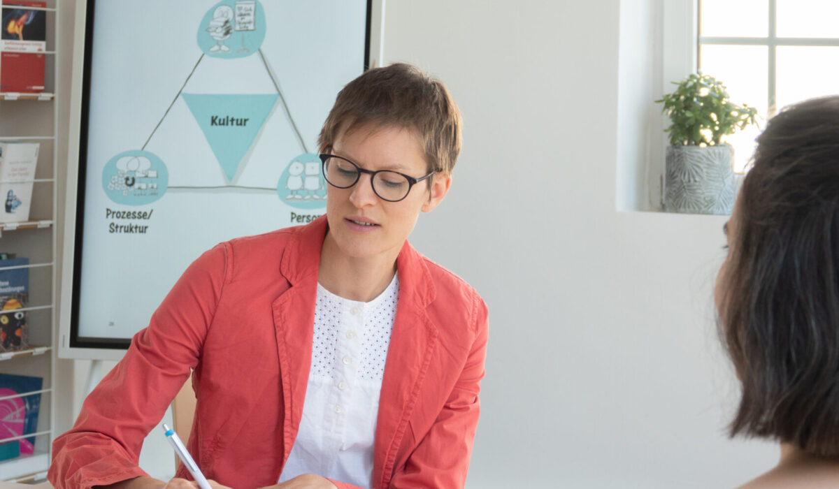 Frau Dr. Teetzen, die an einem Tisch etwas schreibt und ihr gegenüber sitzt eine Frau