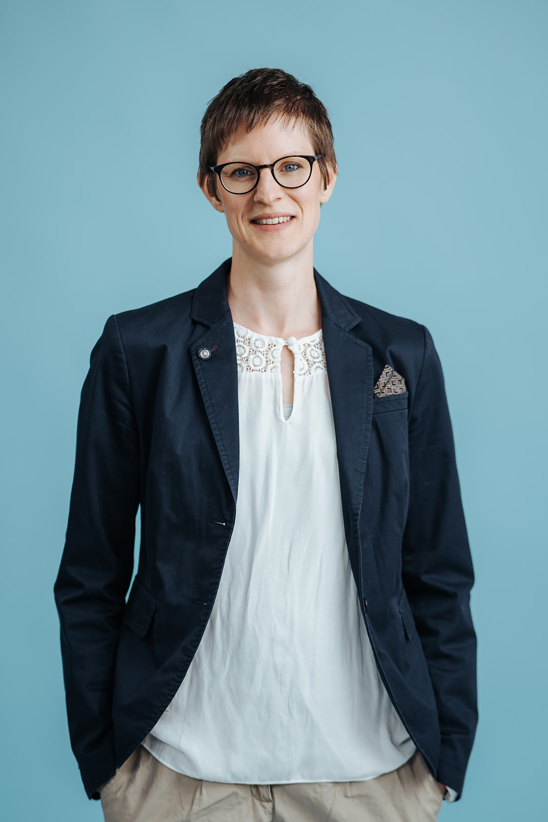Porträtfoto von Dr. Friederike Teetzen für die Teamseite von Heykes&Karstens, stehend vor blauem Hintergrund
