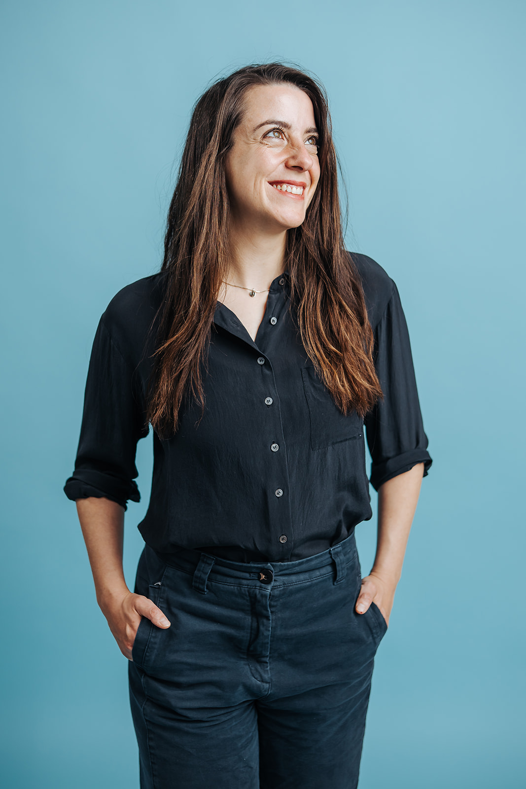 Porträtfoto von Mara Calenic für die Teamseite von Heykes&Karstens, stehend vor blauem Hintergrund