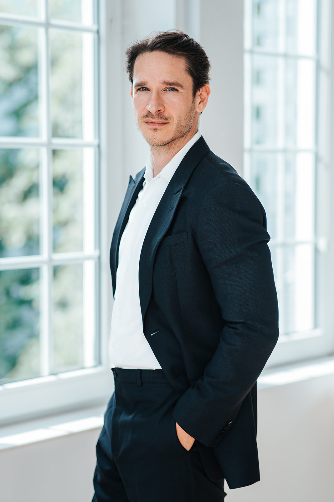 Porträtfoto von Philipp Volotas für die Teamseite von Heykes & Karstens, stehend und im Hintergrund ein Fenster